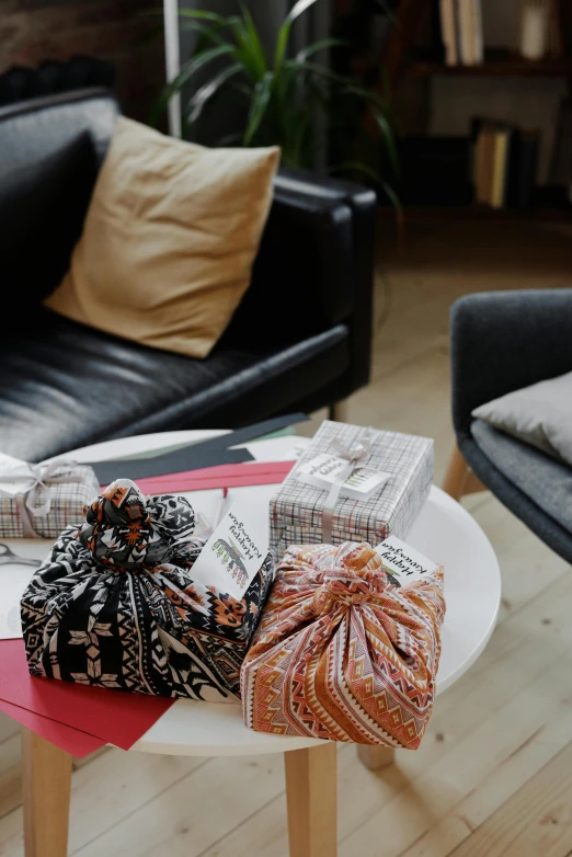 a black couch sitting in a living room next to a coffee table, by Alice Mason, happening, birthday wrapped presents, sustainable materials, panorama, bags