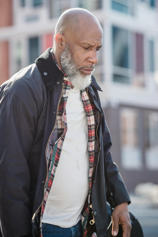 a man with a beard is walking down the street, by Robert Medley, trending on unsplash, gray haired, african american, flannel, concerned