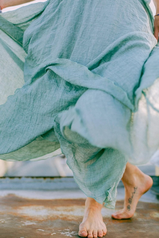 a woman in a blue dress is walking, inspired by Marià Fortuny, unsplash, happening, pale cyan and grey fabric, seafoam green, bottom body close up, dirty linen robes