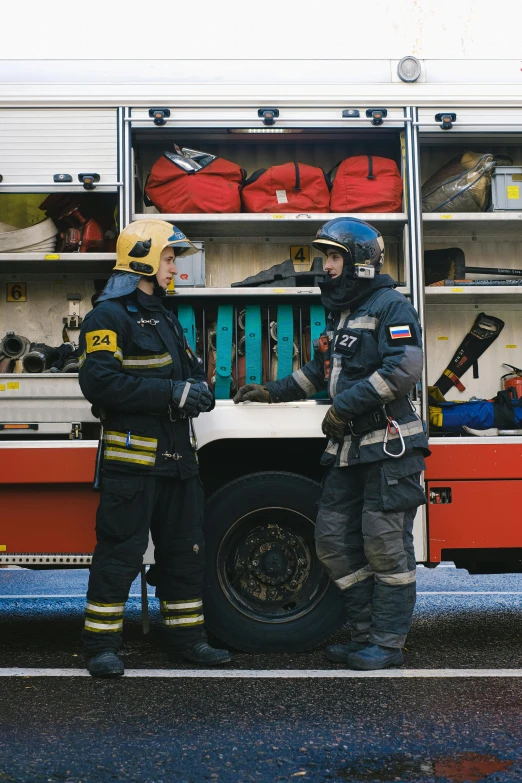 two firefighters standing in front of a fire truck, a photo, by Adam Marczyński, pexels contest winner, happening, technical suit, 🚿🗝📝, caucasian, gif