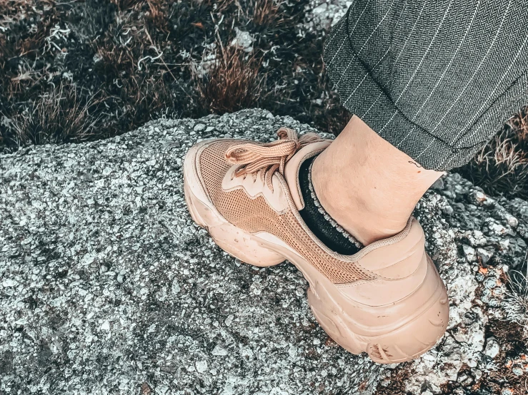 a person standing on top of a rock, trending on pexels, renaissance, gum rubber outsole, in shades of peach, desaturated, bella poarch