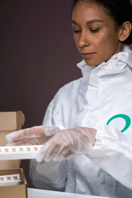 a woman standing in front of a box of doughnuts, a portrait, shutterstock, plasticien, white and teal garment, handling laboratory equipment, wearing nanotech honeycomb robe, small vials and pouches on belt