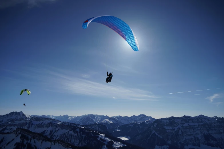 a person that is in the air with a parachute, by Peter Churcher, pexels contest winner, alpes, blue, back lit, cg original