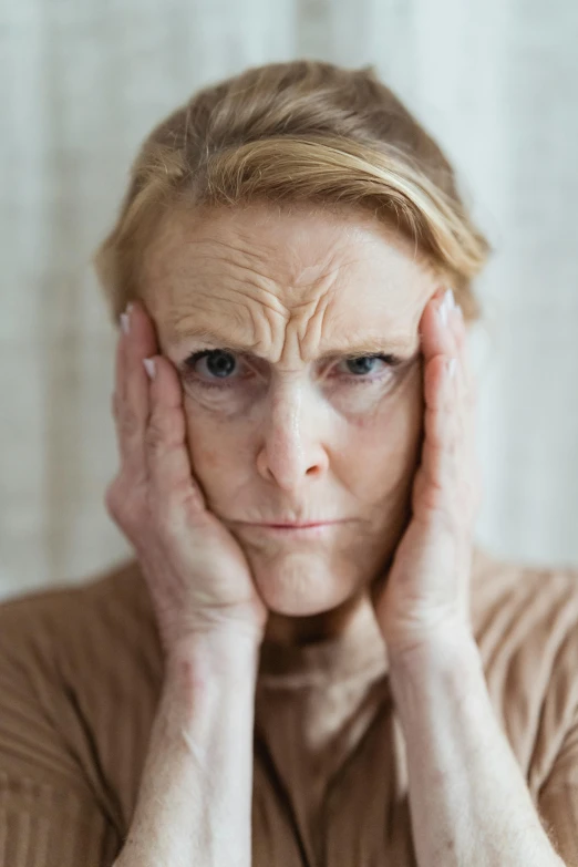 a woman holding her hands to her face, soft but grumpy, aging, horned, square