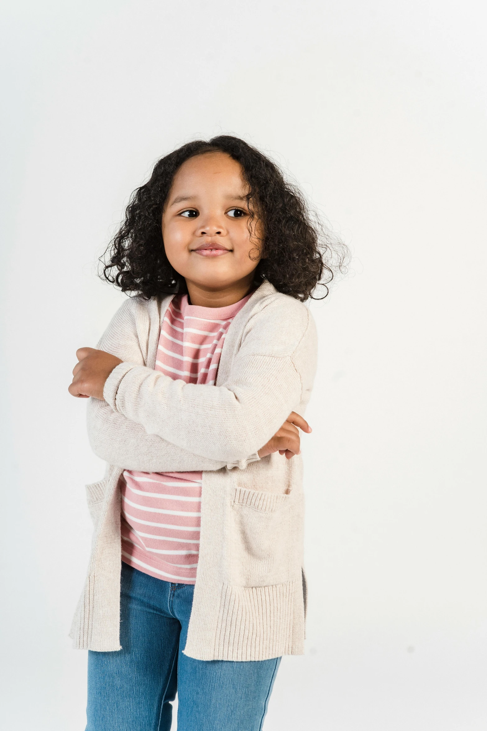 a little girl standing with her arms crossed, wearing a cardigan, promo image, diverse, ready to model