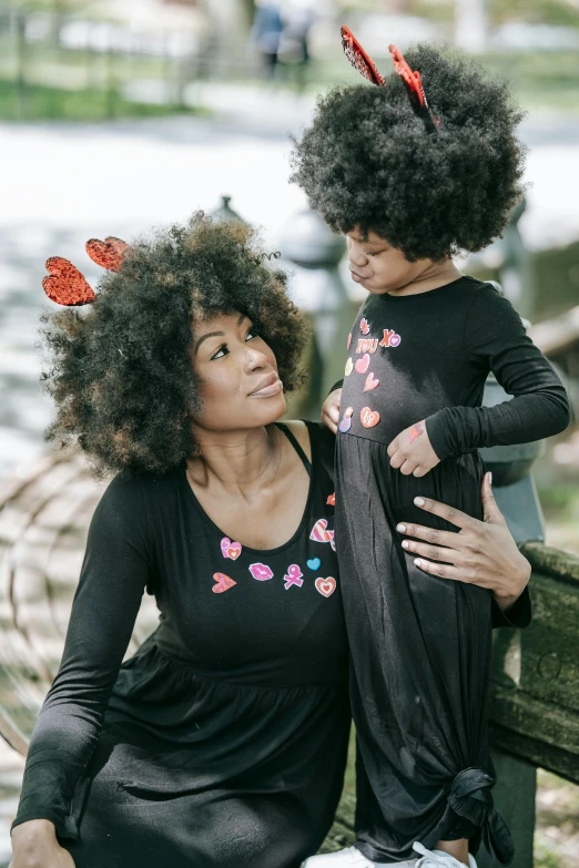 a woman and a child sitting on a bench, afro made of flowers, casual black clothing, hearts, 2019 trending photo