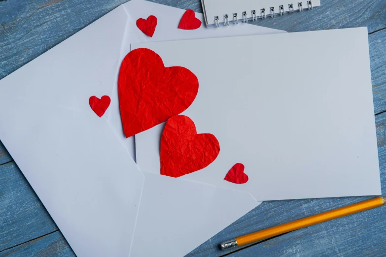 two white envelopes with red hearts and a pencil on a blue wooden table, by Julia Pishtar, pixabay, mail art, 9 9 designs, thumbnail, background image