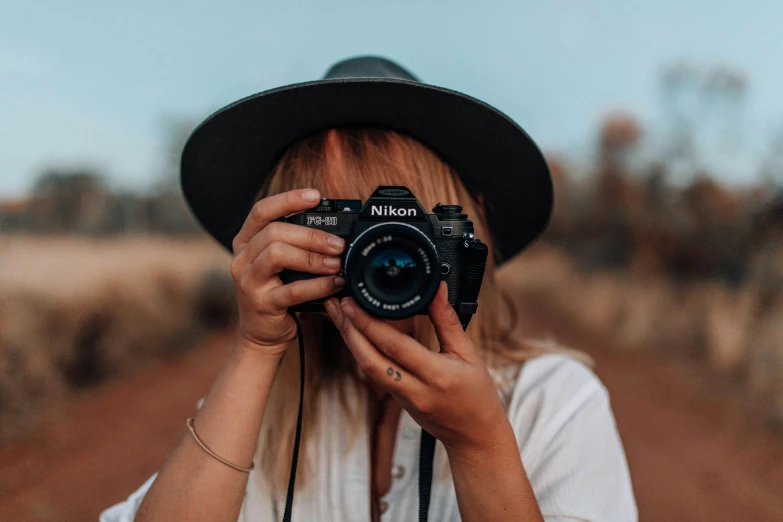 a woman taking a picture with a camera, unsplash contest winner, nikon camera, 🤠 using a 🖥, headshot, traveller