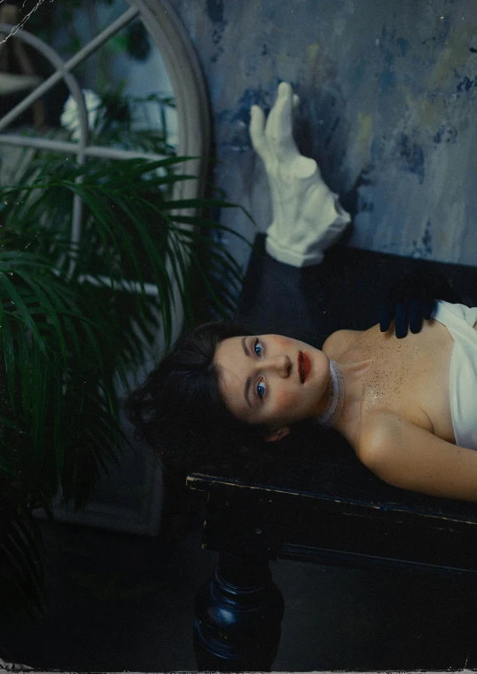 a woman laying on top of a black table, a surrealist painting, inspired by Elsa Bleda, unsplash, film still from horror movie, valentin serov style, shohreh aghdashloo, plastic skin