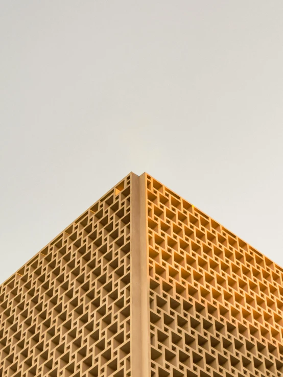 a tall building with a clock on top of it, an album cover, trending on unsplash, brutalism, honeycomb structure, light - brown wall, gold, high quality photo