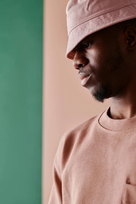 a close up of a person wearing a hat, inspired by Paul Georges, trending on pexels, looking to his side, muted pastels, man standing, mc ride