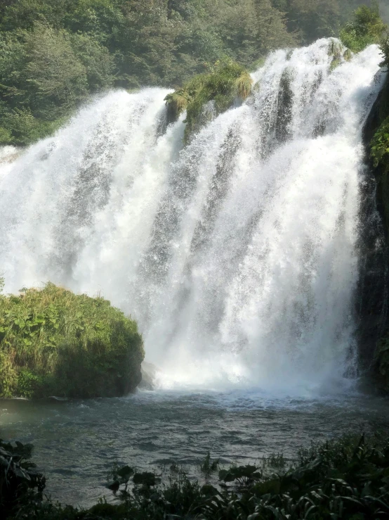 a large waterfall in the middle of a lush green forest, hurufiyya, white travertine terraces, facing front, fishing, up-close