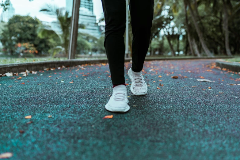 a person walking on a road with trees in the background, wearing white sneakers, background image, working out, multiple stories