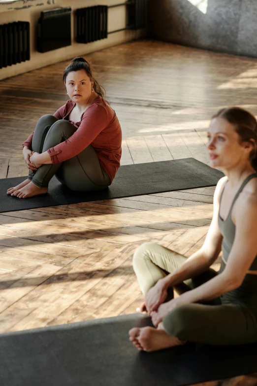 two women sitting on yoga mats in a room, cinematic movie still, high-quality photo, concerned expression, promotional image