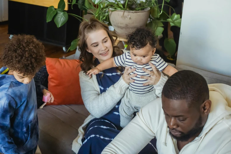 a group of people sitting on top of a couch, babies in her lap, black man, avatar image, caring fatherly wide forehead