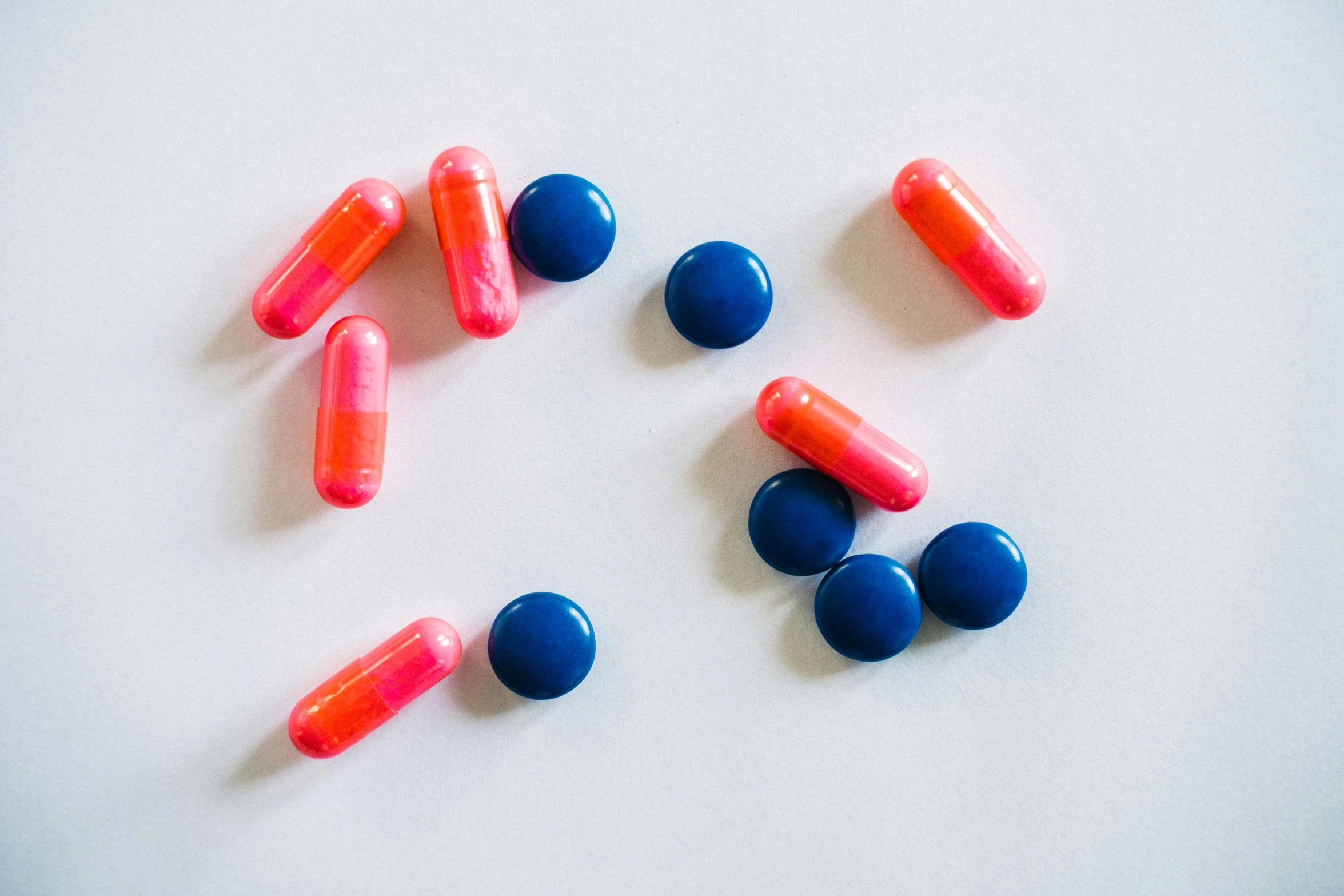 a group of pills sitting on top of a white surface, by Rachel Reckitt, antipodeans, fuchsia and blue, dark blue + dark orange, thin blue arteries, nootropic stimulant