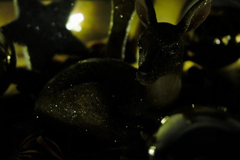 a close up of a rabbit figurine on a table, a macro photograph, by Adam Marczyński, pexels contest winner, golden orbs and fireflies, australian winter night, shiny scales, dark doe eyes