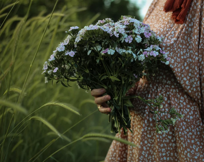 a woman holding a bunch of flowers in a field, inspired by Elsa Bleda, visual art, brown, verbena, cottagecore flower garden, uncropped