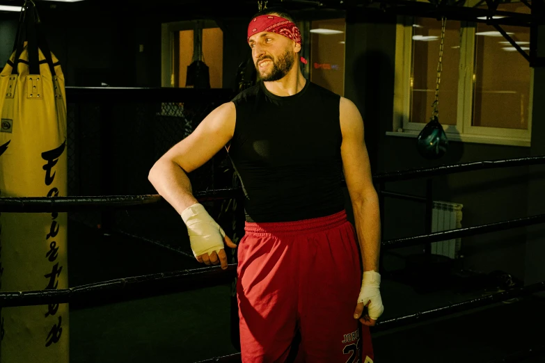 a man standing in a boxing ring next to a punching bag, inspired by Volkan Baga, rasputin as grubhub character, looking away from the camera, profile image, [ theatrical ]