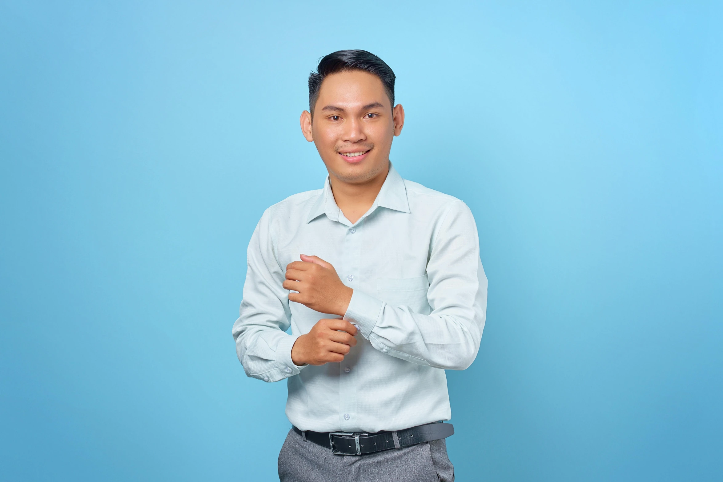 a man standing in front of a blue background, by Basuki Abdullah, office clothes, young male, uploaded, friendly smile