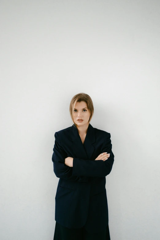 a woman standing in front of a white wall, an album cover, in strict suit, serious expression, kirsi salonen, transparent background