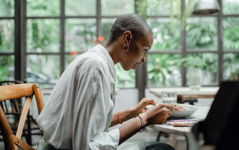 a woman sitting at a table in front of a laptop, pexels contest winner, plating, portrait of ororo munroe, side profile view, people sitting at tables