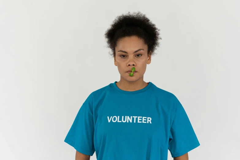 a woman with a piece of broccoli in her mouth, an album cover, by Ellen Gallagher, pexels contest winner, teal uniform, virgil abloh, tshirt, hunger