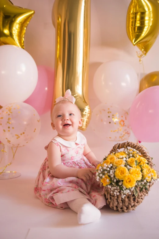 a baby girl sitting in front of a bunch of balloons, gold flaked flowers, pink and yellow, portrait image, one