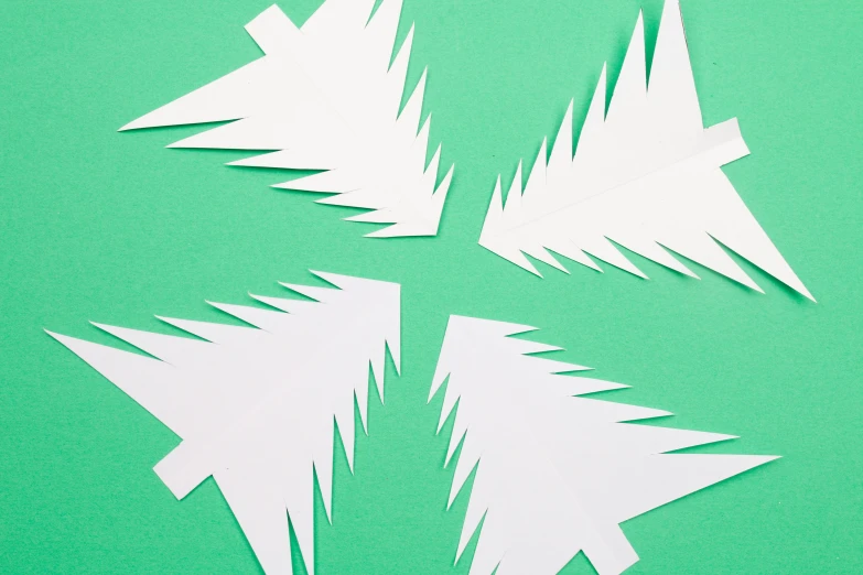 four white paper christmas trees on a green background, by Julia Pishtar, trending on pexels, hurufiyya, arrow shaped, cuts, white background : 3, cirno