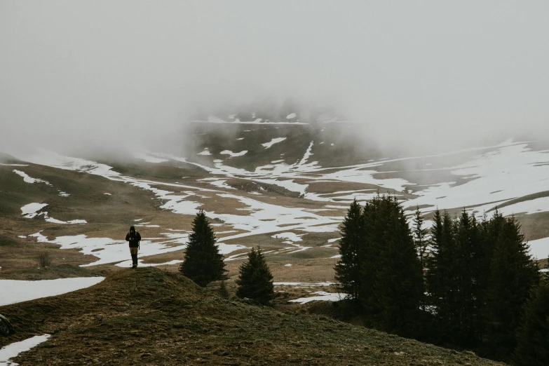 a person standing on top of a snow covered hill, by Emma Andijewska, pexels contest winner, overcast day, in the dolomites, fog and dirt, hunting