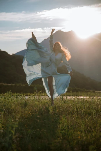 a woman standing on top of a lush green field, an album cover, unsplash contest winner, arabesque, dancing gracefully, blocking the sun, flowing fabric, grey
