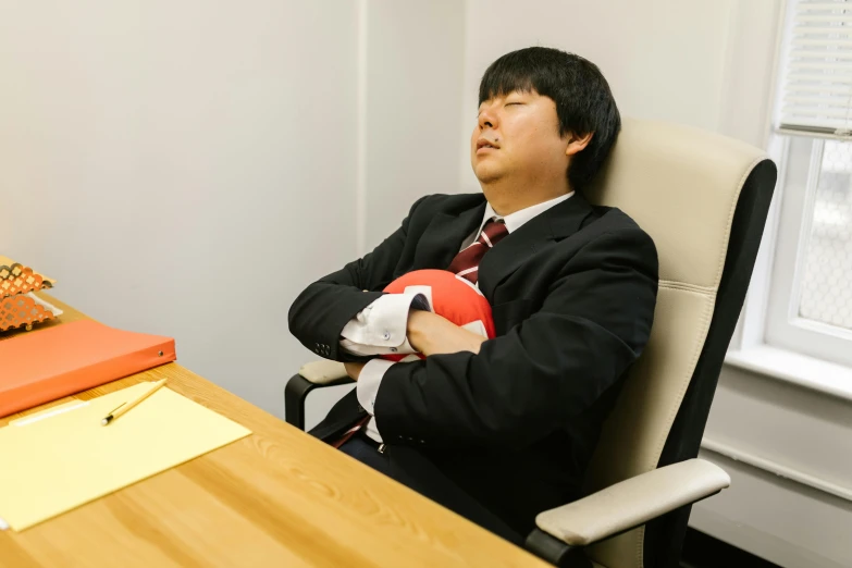 a man in a suit sitting at a desk with a ball, unsplash, shin hanga, asleep, narumi kakinouchi, cosplay photo, ai researcher