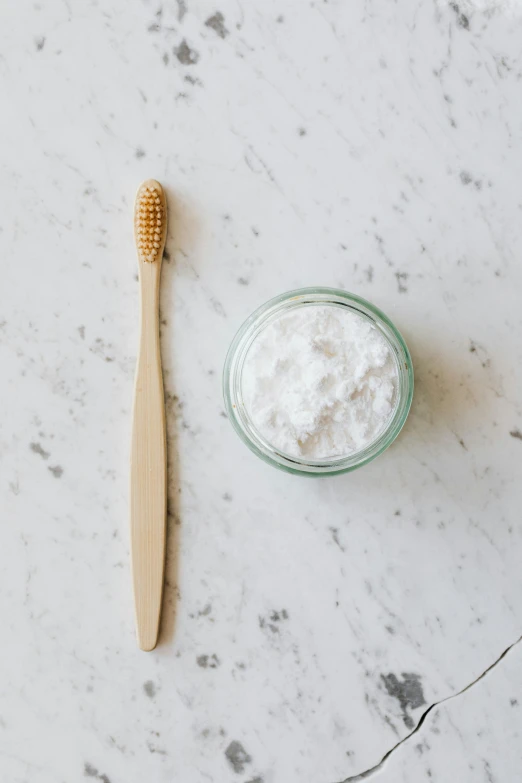 a toothbrush sitting next to a jar of toothpaste, by Nicolette Macnamara, unsplash, natural materials, flour dust, flat lay, with white