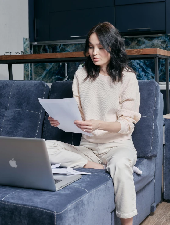 a woman sitting on a couch with a laptop, inspired by Fei Danxu, happening, wear's beige shirt, papers, wearing off - white style, portrait featured on unsplash