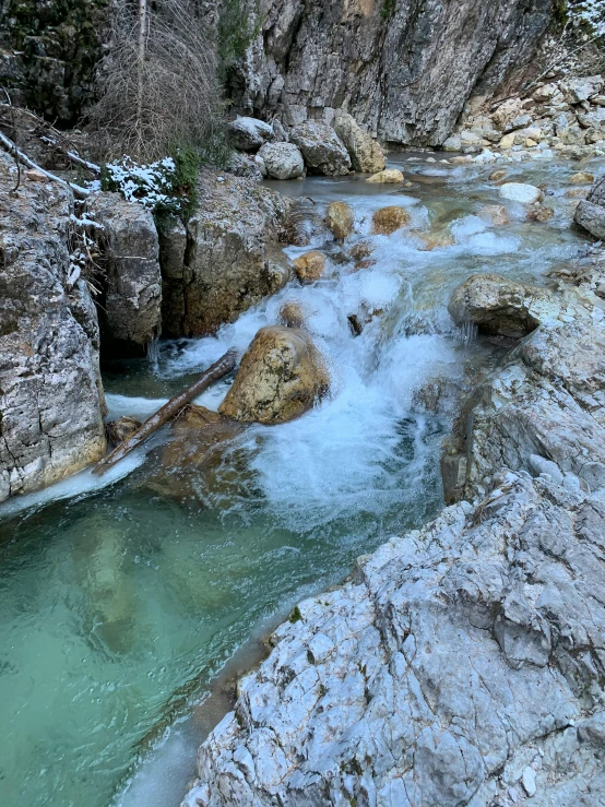 a river running through a rocky canyon next to a forest, a picture, inspired by January Suchodolski, pexels contest winner, icy, white travertine terraces, thumbnail, no filter