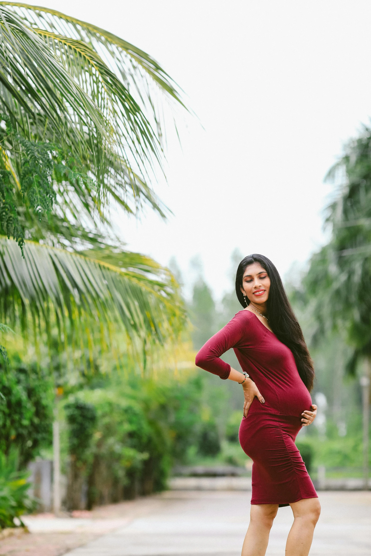 a woman in a red dress posing for a picture, maternity feeling, with palm trees in the back, avatar image, nivanh chanthara