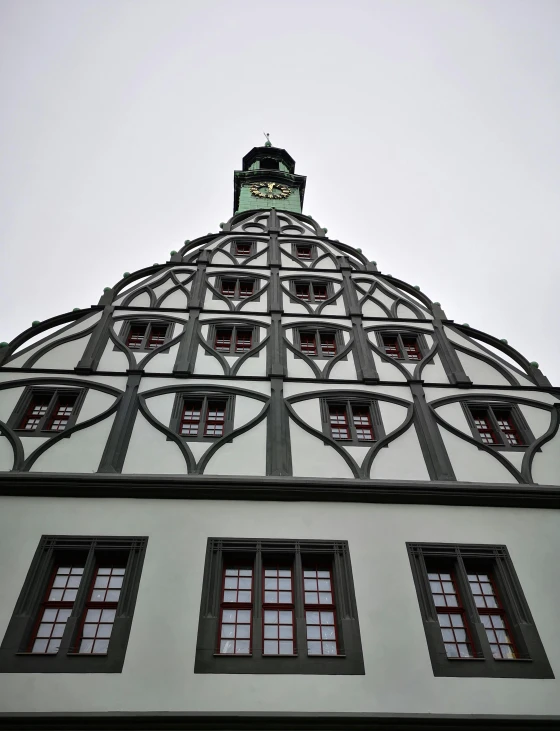 a tall building with a clock on top of it, detmold, full of greenish liquid, tiny ornate windows, under a gray foggy sky