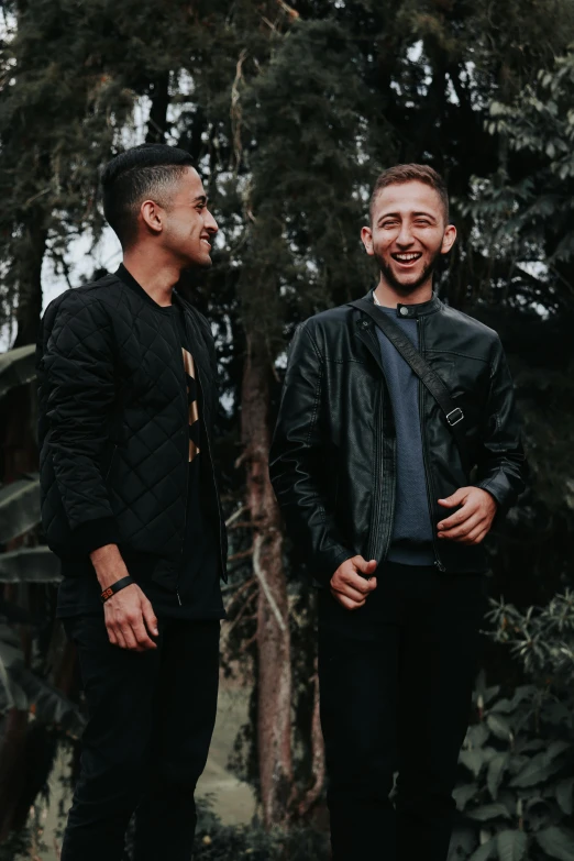 two men standing next to each other in front of trees, pexels contest winner, antipodeans, wearing a leather jacket, mutahar laughing, pablo carpio and jordan grimmer, profile image