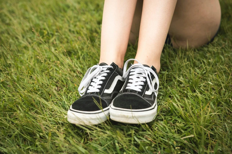 a woman sitting on top of a lush green field, an album cover, pexels, realism, sneaker shoes, wearing black shorts, closeup - view, ( ultra realistic