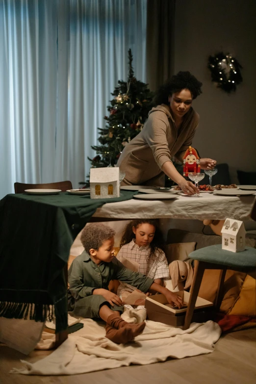 a woman and two children sitting at a table in front of a christmas tree, pexels contest winner, realism, with furniture overturned, tabletop model, inspect in inventory image, people sitting at tables