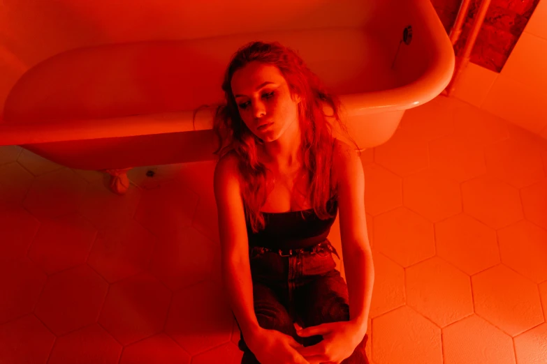 a woman sitting on a toilet in a bathroom, an album cover, inspired by Nan Goldin, antipodeans, glowing red, portrait sophie mudd, scene from fightclub movie, orange hue