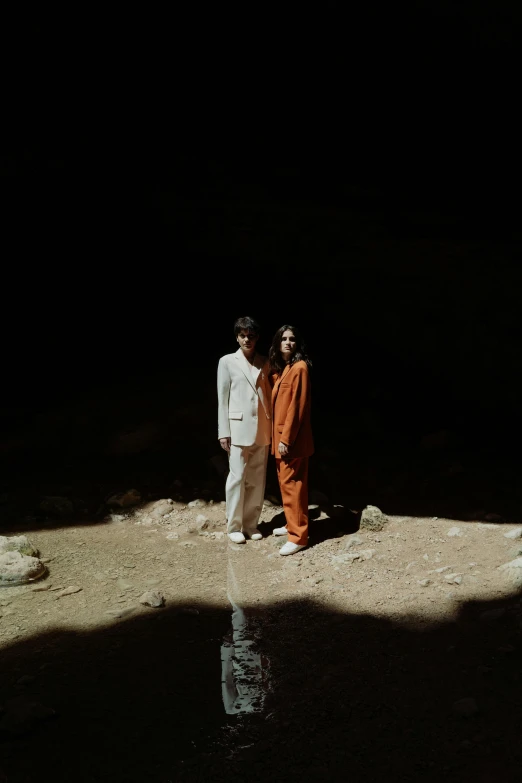 a couple of people standing next to a body of water, an album cover, unsplash, dau-al-set, in a large desert cave, wearing white suit, lee madgwick & liam wong, taken with kodak portra