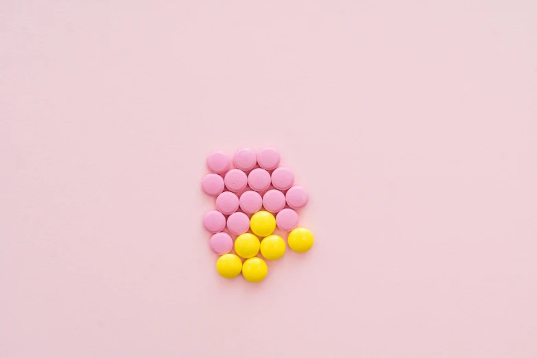 pink and yellow pills on a pink surface, by Nicolette Macnamara, antipodeans, chocolate, mid-20s, vanilla, on grey background