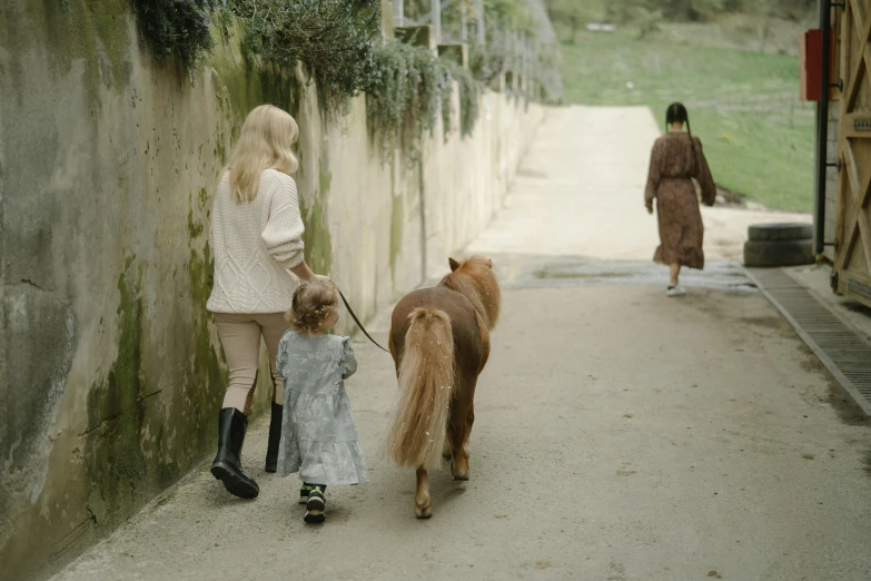 a woman walking two ponies down a street, unsplash, scene from live action movie, walking at the garden, families playing, shot on sony a 7