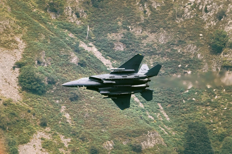 a fighter jet flying over a lush green hillside, whistler, top gun maverick, cfd, wales