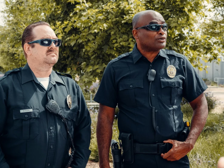 two police officers standing next to each other, by Carey Morris, pexels, implanted sunglasses, diverse, netflix, overlooking