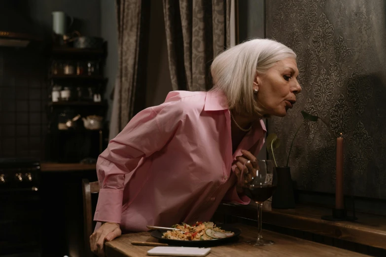 a woman sitting at a table with a plate of food and a glass of wine, pexels contest winner, spit flying from mouth, white haired, bent over posture, profile image