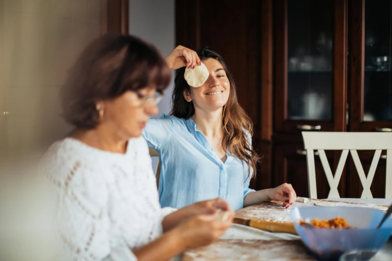 two women sitting at a table in front of a laptop, a picture, pexels contest winner, renaissance, cooking pizza, polka dot, over-the-shoulder-shot, in the shape of a cinnamon roll