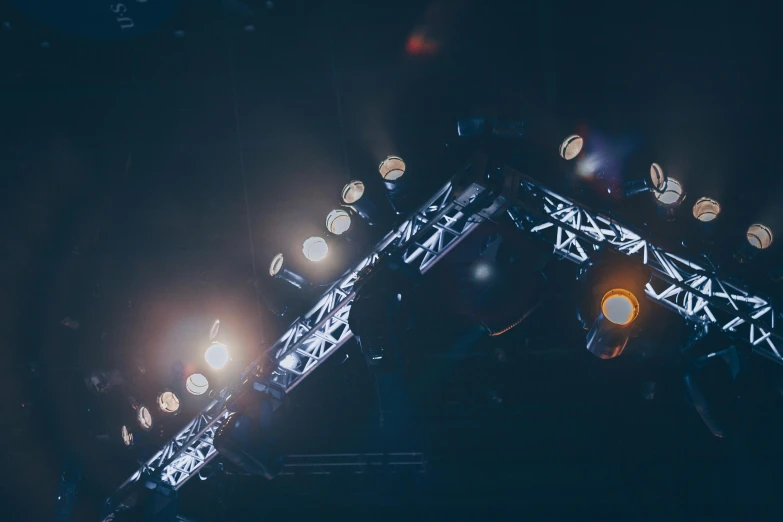 a group of people standing on top of a stage, by Adam Marczyński, pexels contest winner, light and space, dark cables hanging from ceiling, volumetric search lights, concert light, instagram post