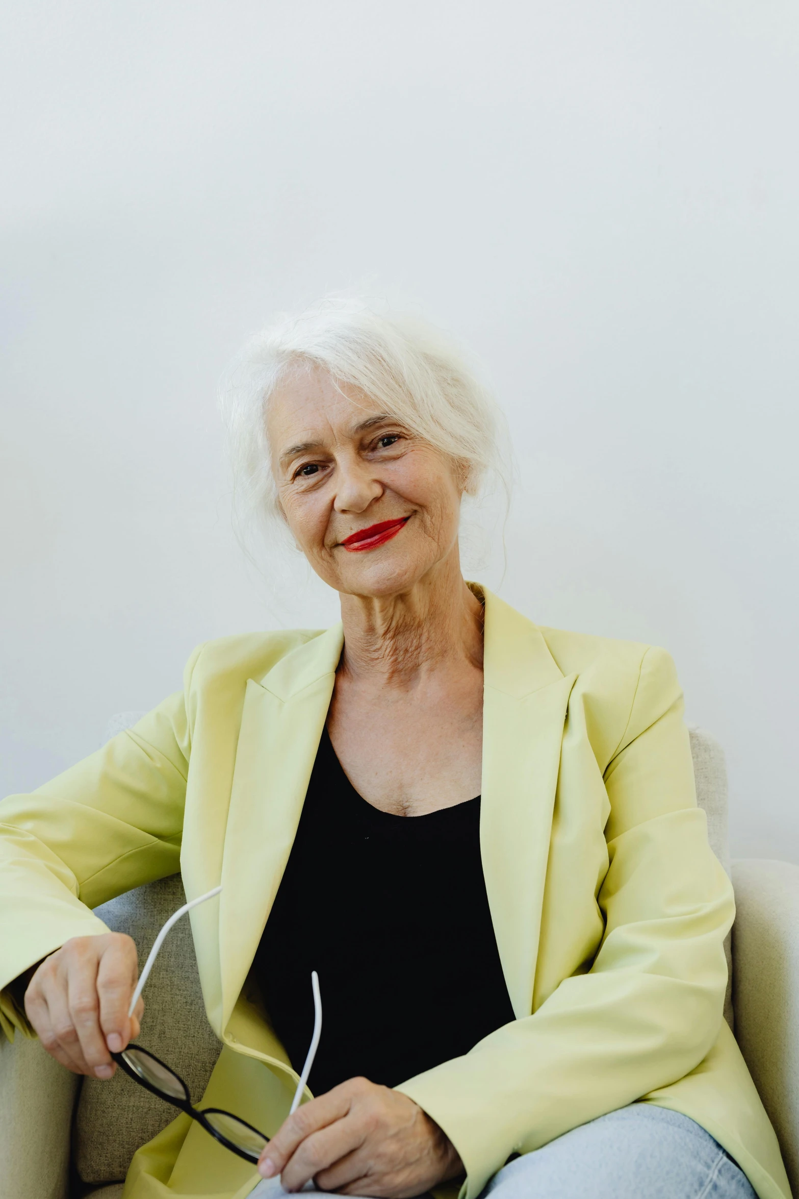 a woman in a yellow jacket sitting on a couch, long length slick white hair, royal commission, on a white table, joyful smirk